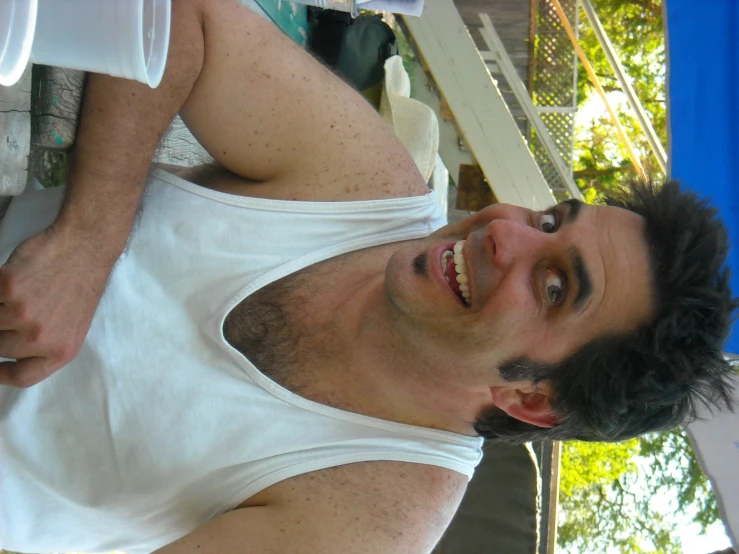 a man with curly hair and white shirt sitting on a chair