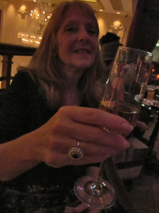 a woman in a bar holding a glass of white wine