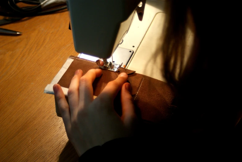 woman using sewing machine in room on wooden table