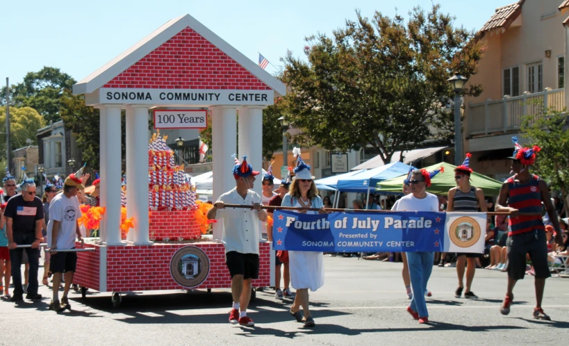 a parade with float in background, on a street