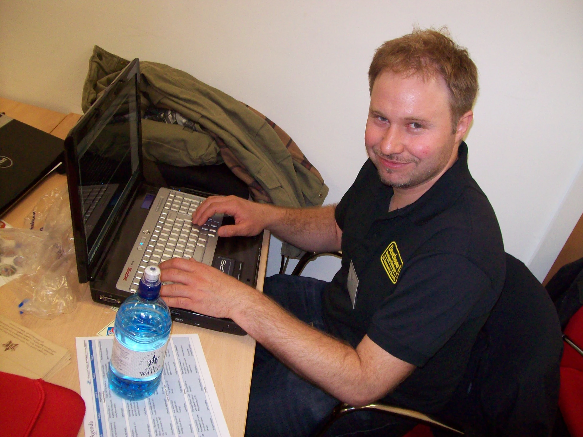 a man sits with a laptop computer and drinks water