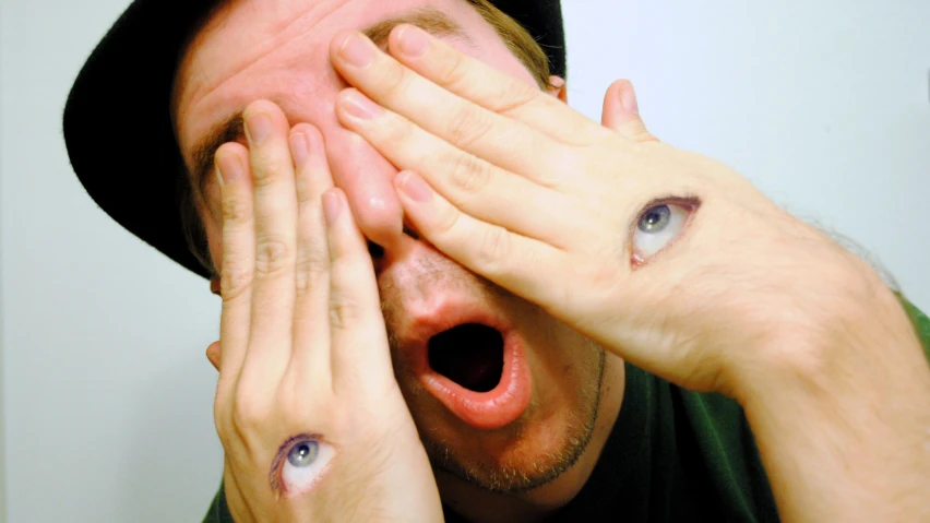 a man and woman holding their hands together while covering their eyes