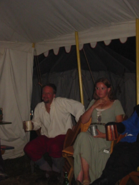 people sitting in chairs under a tent at night