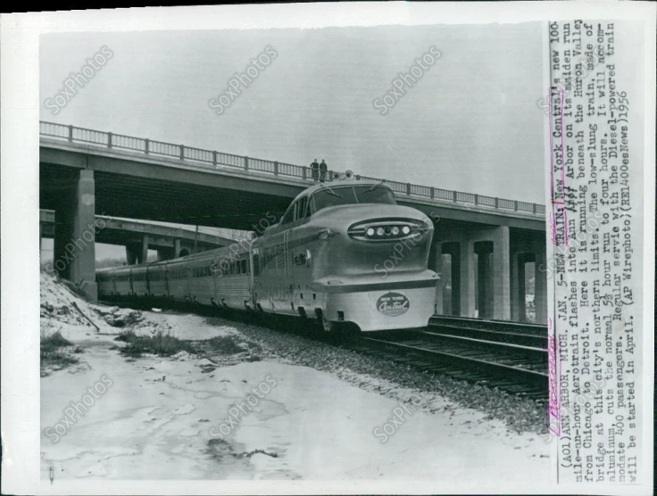 black and white po of train passing under a bridge