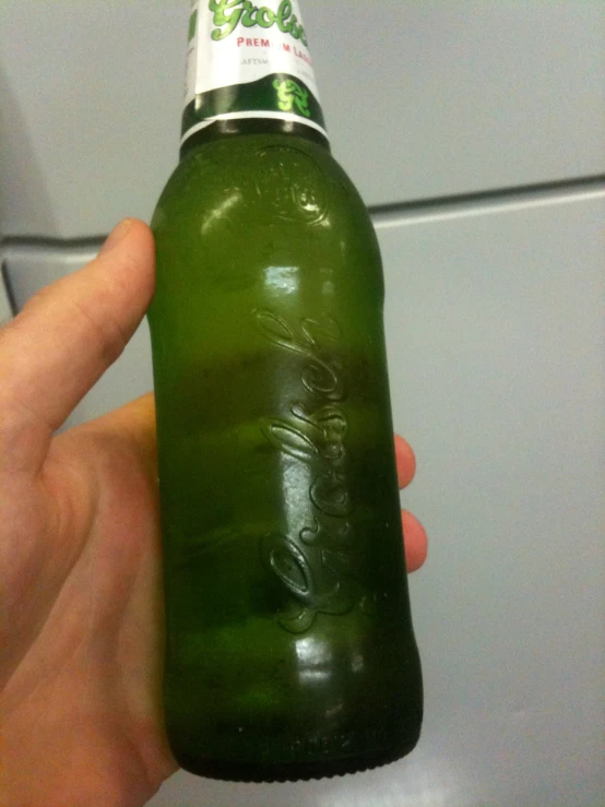 the hand is holding up a green bottle