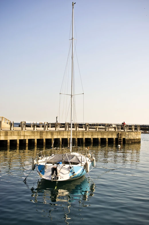 a small boat sits in the water by a pier