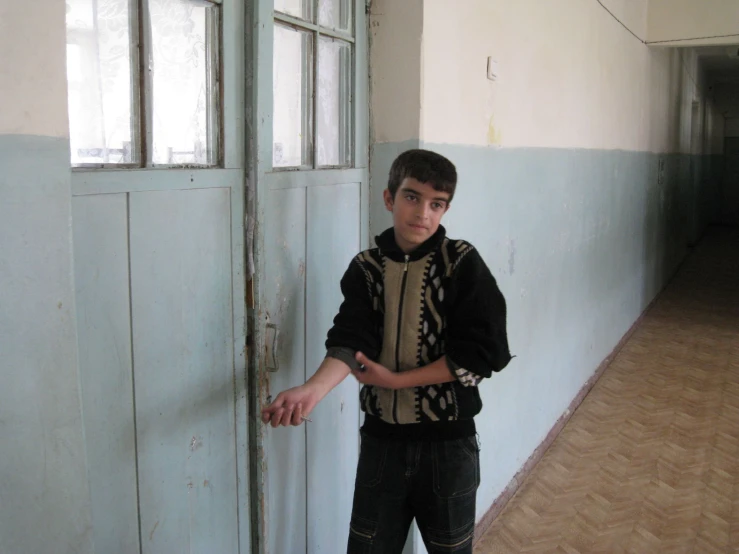 a young man poses for a pograph next to a door