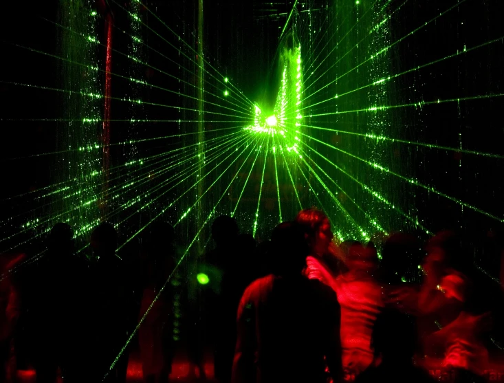 people standing around using laser lights in a dark area