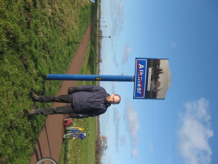 man standing next to a blue street sign