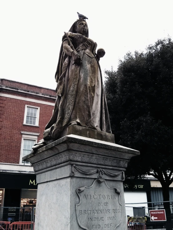 the statue is on a pedestal near a building