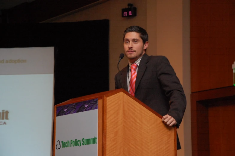 a man in suit and tie standing at a podium