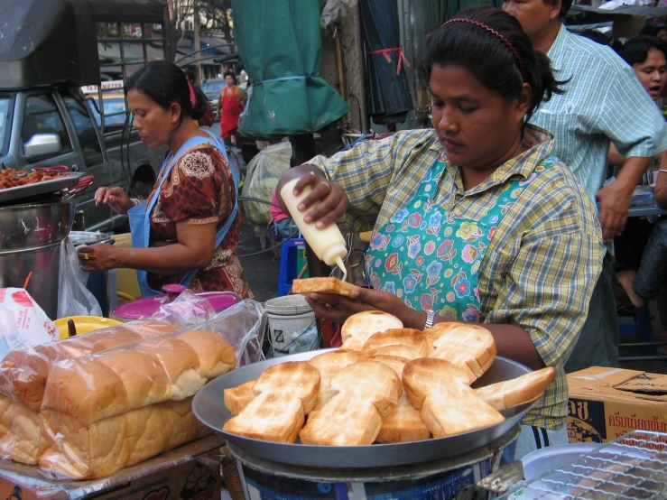 a woman stands at a vendor selling bread