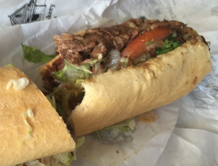 a meat sandwich on toasted paper on top of a table