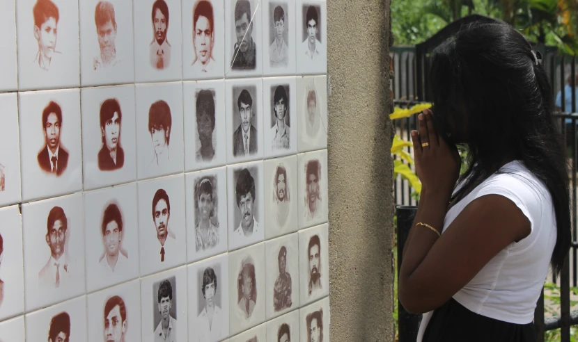 a woman looking up at the side of a wall with portraits on it