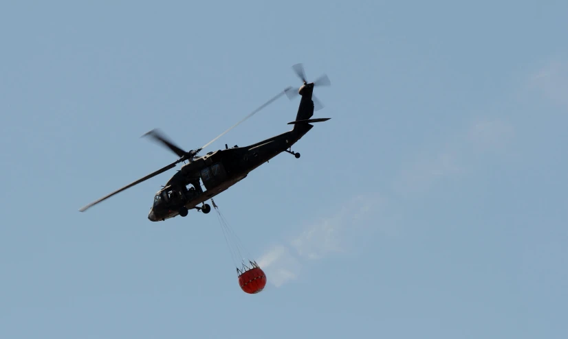 a helicopter drops a red round object into the air