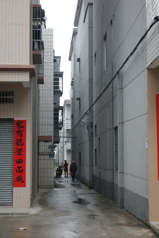 two people walking down a walkway between tall buildings