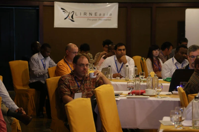 people sitting at tables with a number of laptops