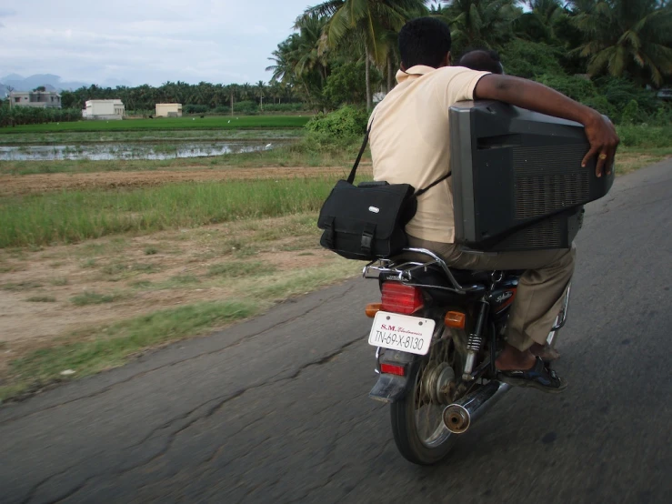 a man on a motorbike on a road with a television