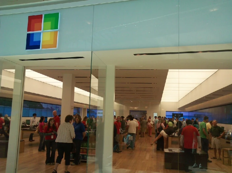 several people walk through a window that shows a microsoft logo