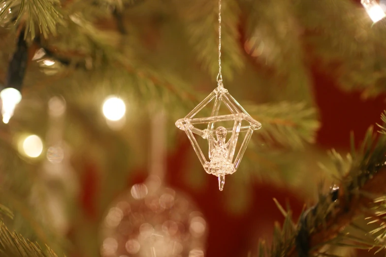 the small glass ornament is suspended from the tree