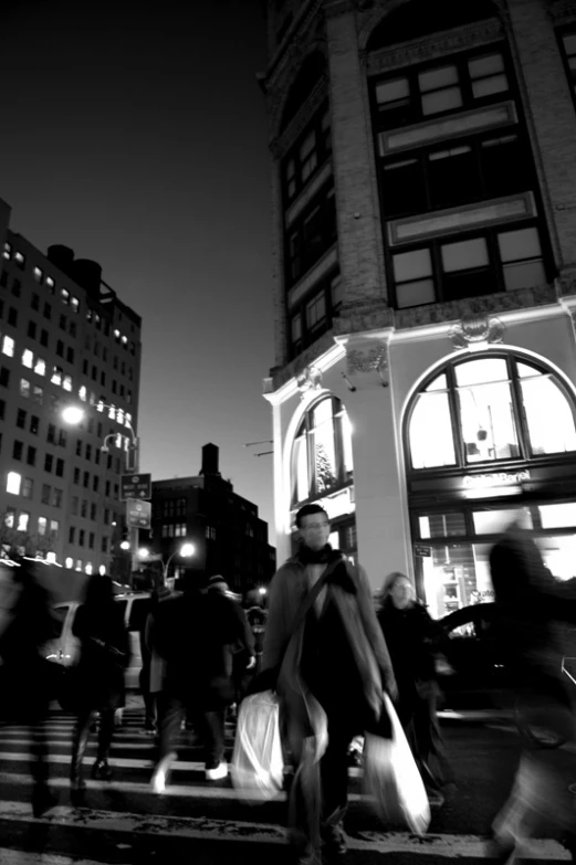 a number of people walking down the street near some tall buildings