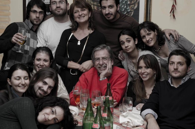 the group has several people around a table full of wine bottles and glasses