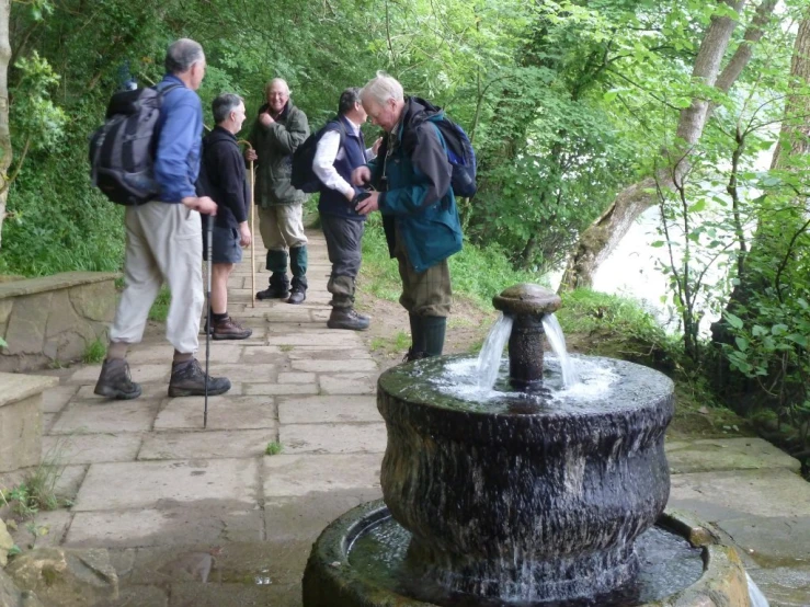 several people are standing around looking at a fountain