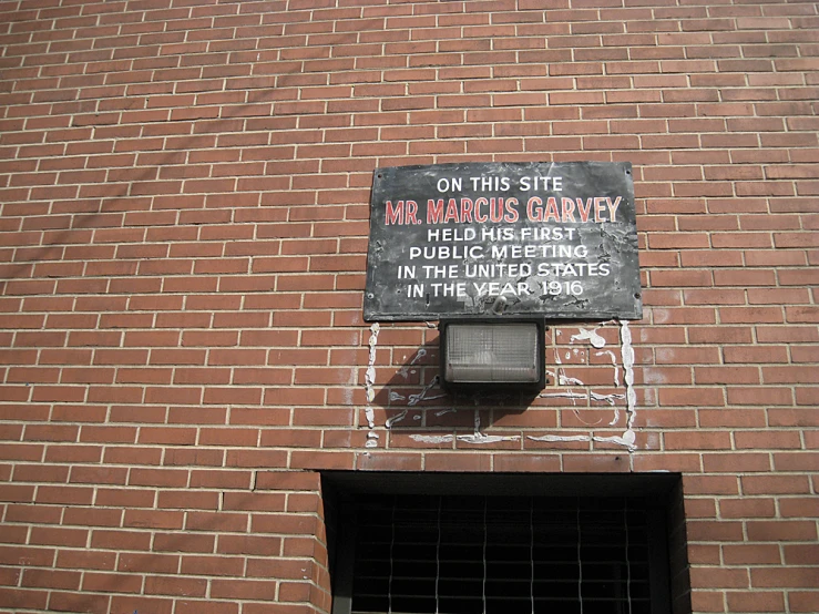 a brick wall has a sign hanging on the side