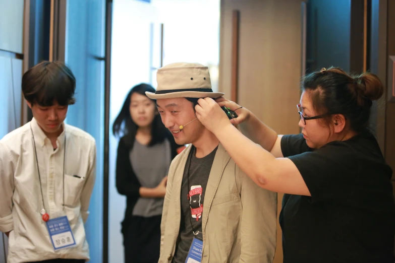 a man in a hat talking on a phone while three other people stand around