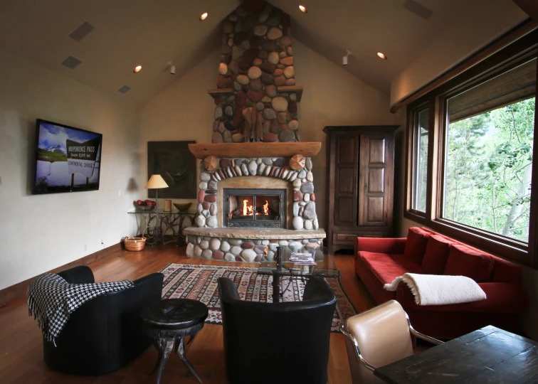 the living room has stone fireplace with red chairs