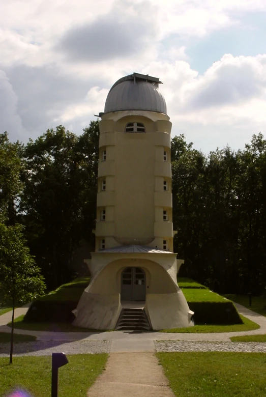 a tall tower with some green grass and trees in the background