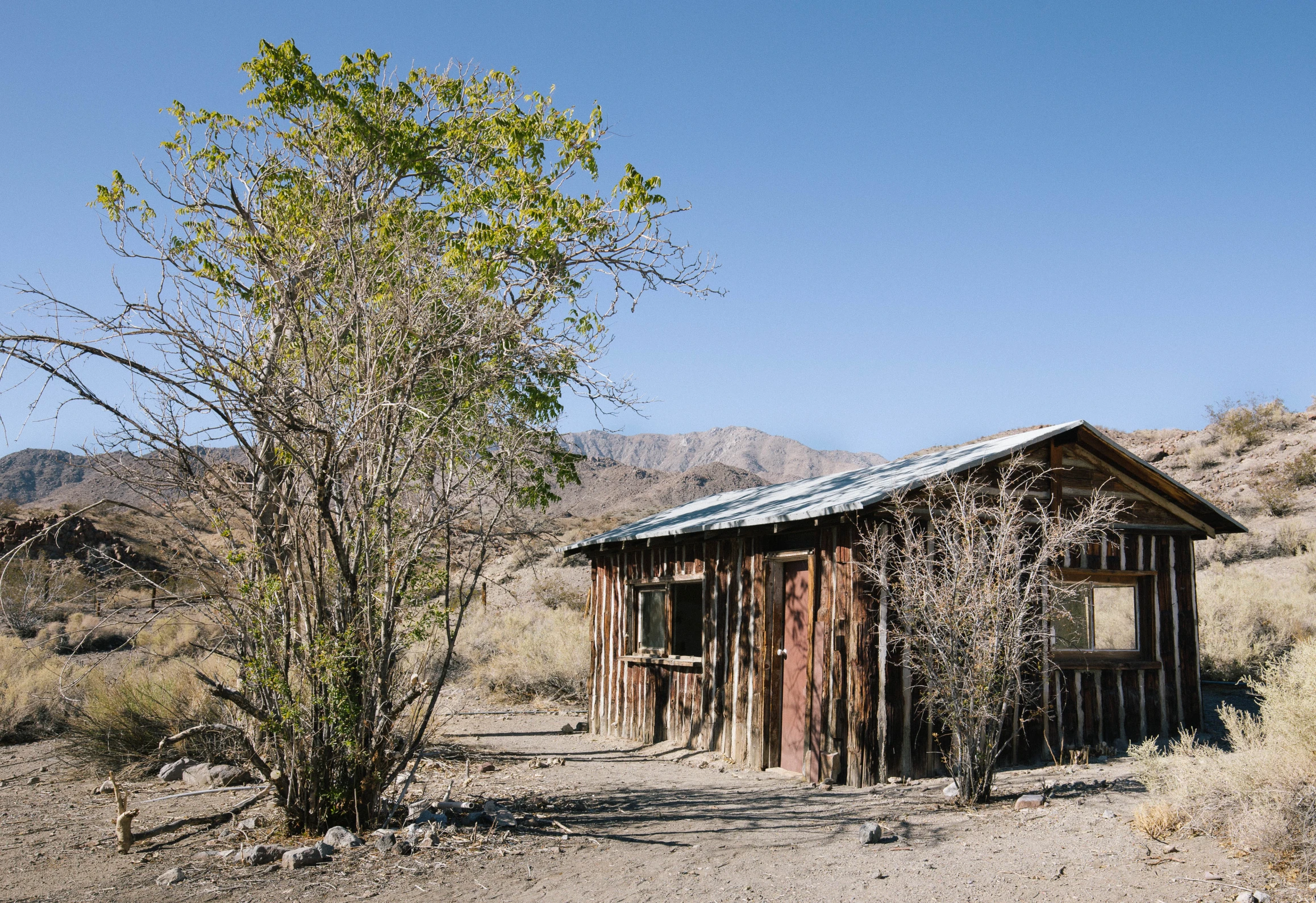 the outside of a wooden cabin on dirt path