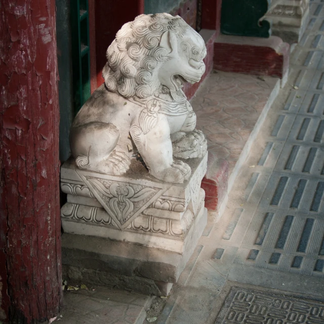 a stone lion sitting on a step next to a building