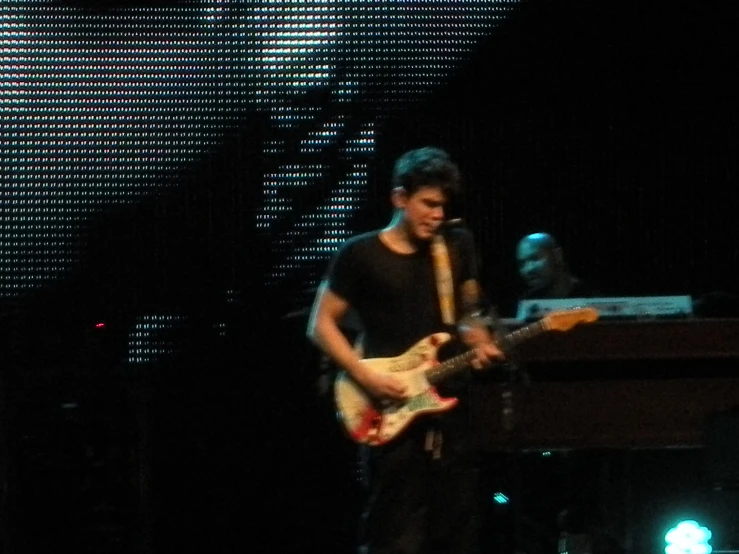 man with guitar standing on stage during the night