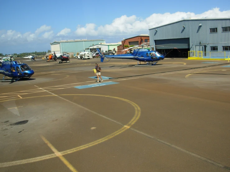 a man stands outside an airfield with small helicopter