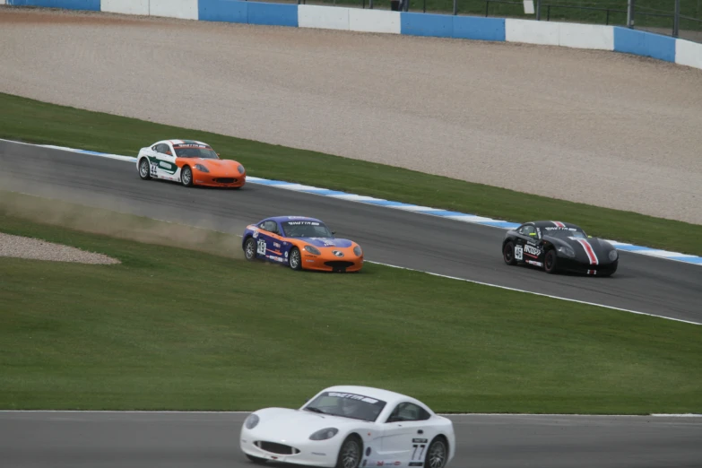 three sport cars racing around a race track