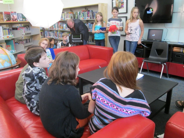 a group of people sitting around a room full of books