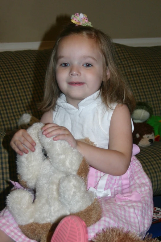 a girl is holding a teddy bear on the couch