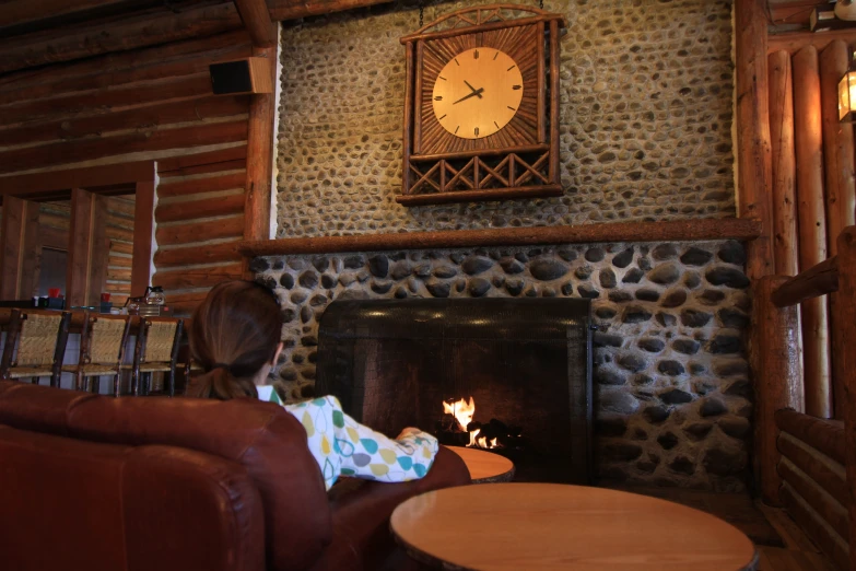 a little girl looks out at the fireplace, which has a large stone clock on it