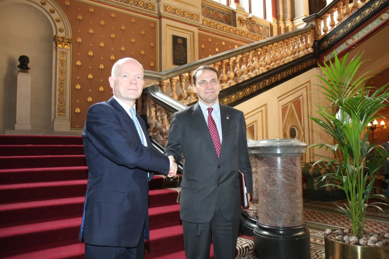 two men are shaking hands near steps