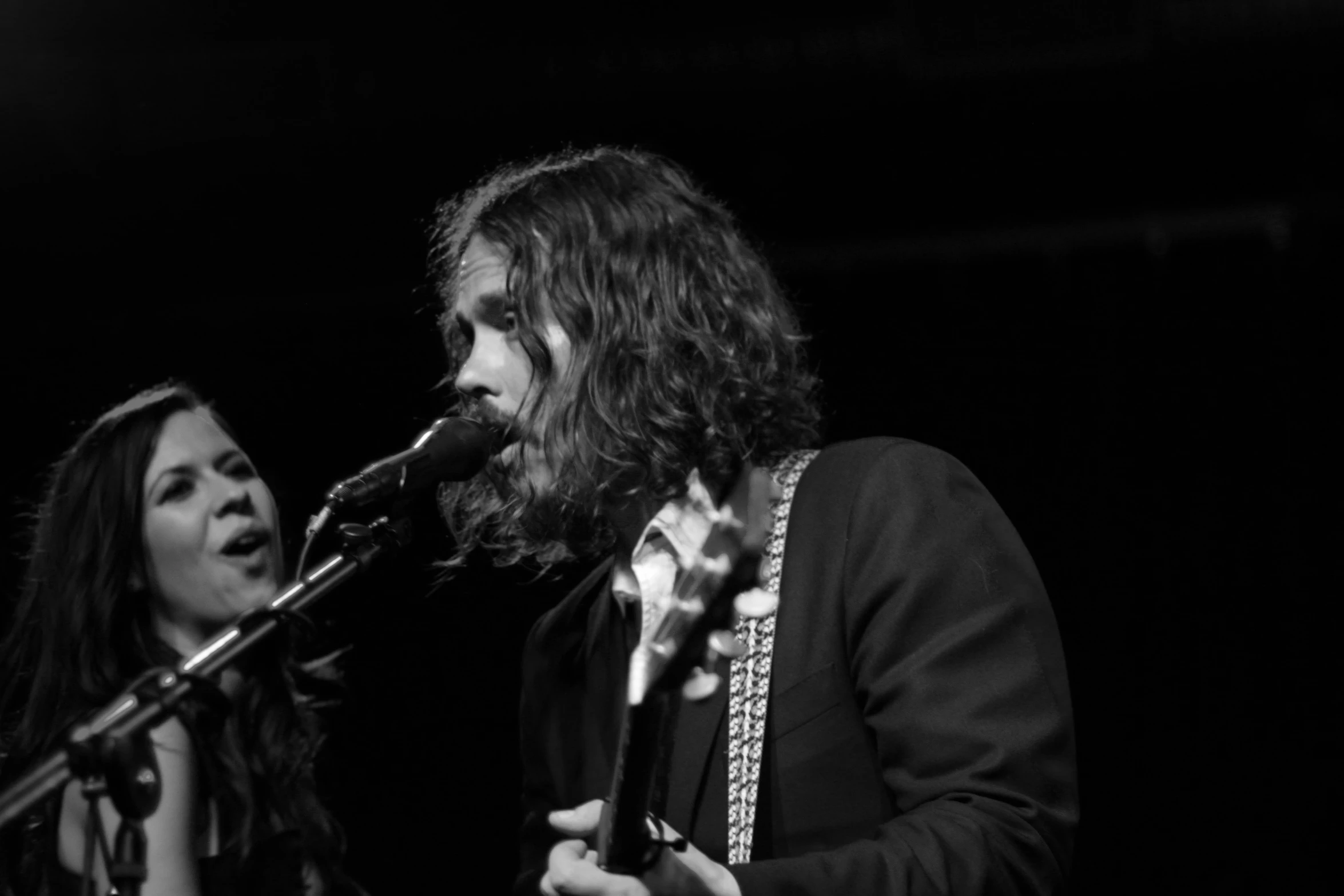 a man and woman singing into microphones at a concert