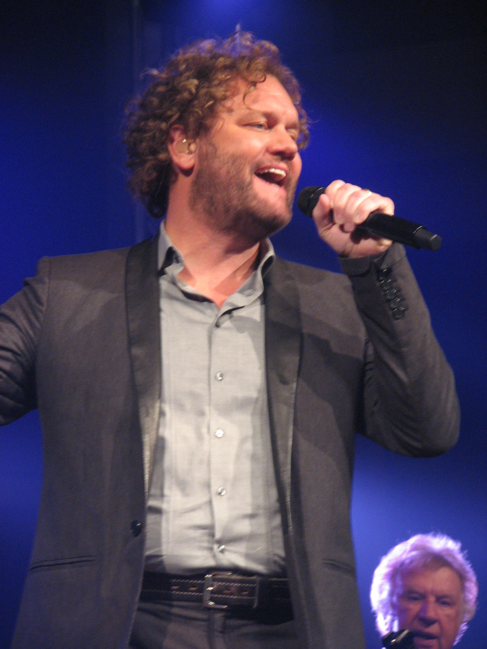 a man that is on stage singing into some microphone