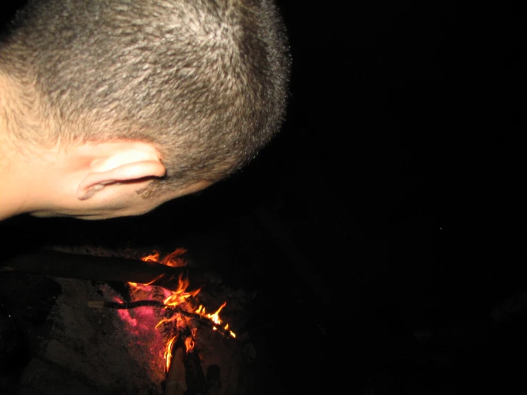 a man is holding a red and yellow lit object over fire