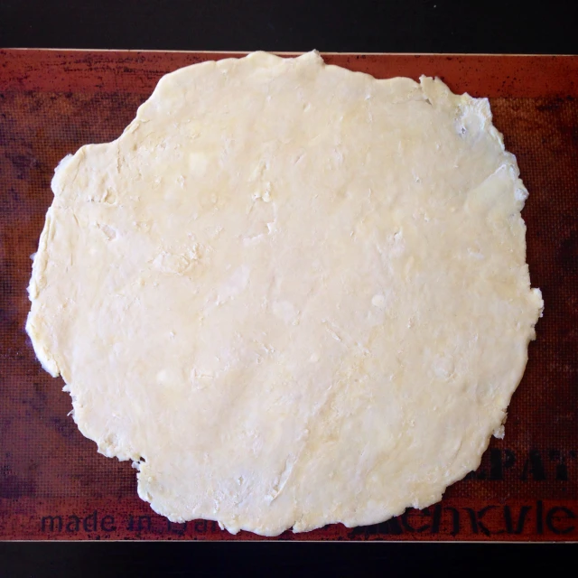 dough is laid on a  board with a wooden  board in the background