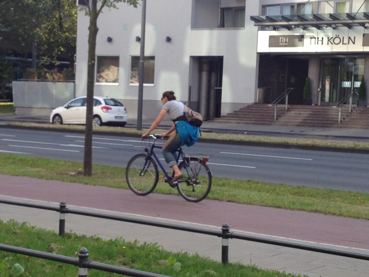 a man riding his bike down the street next to a parking lot