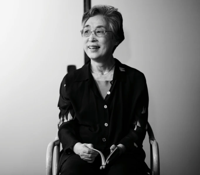a woman sitting in a chair, wearing glasses