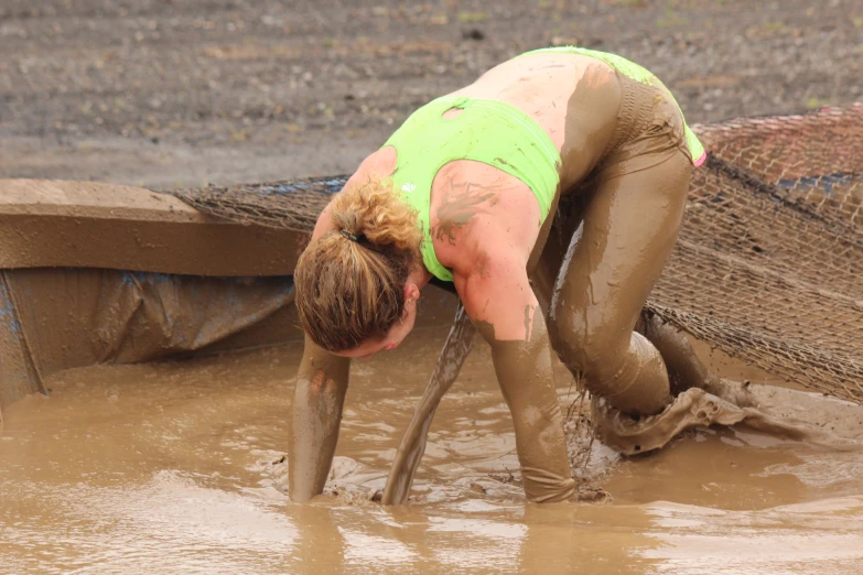 a woman bent down in mud with a pair of shoes