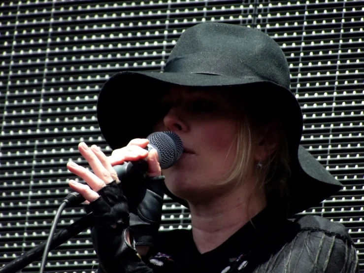 a woman wearing a hat singing into a microphone