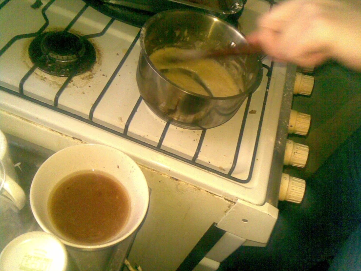 a cup of coffee being held by a hand in front of a stove