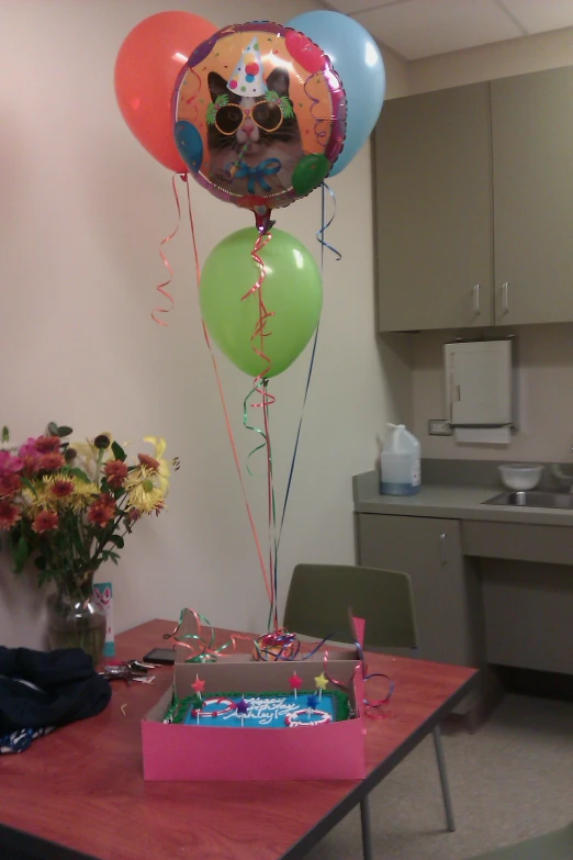 a table filled with balloons, flowers and an open box